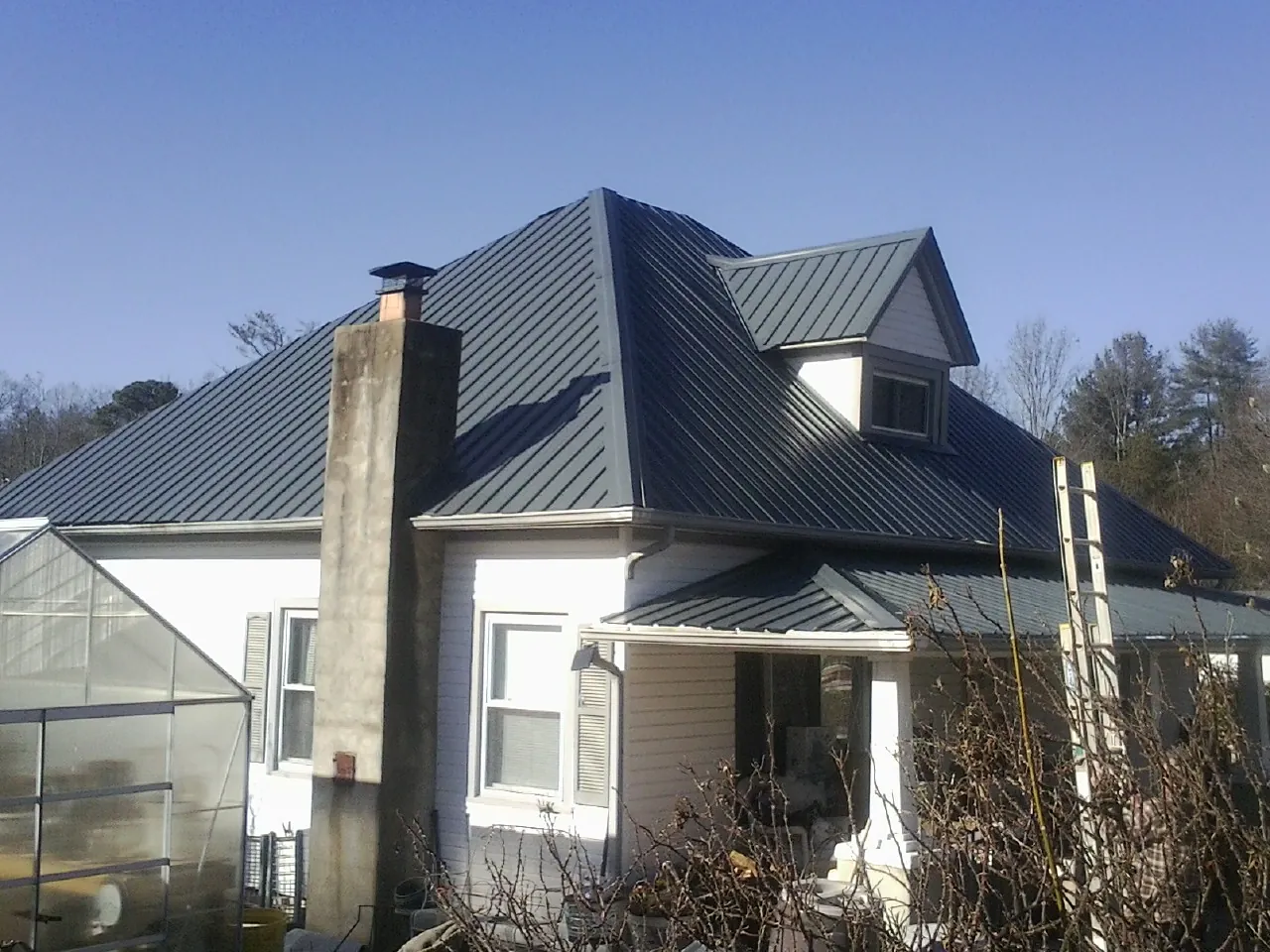 Dark blue standing seam metal roof on a white farmhouse with dormer — Slate & Tile Roof Repair by Roofing Brothers in Birds Landing