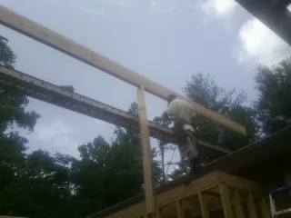 Carpenter setting a ridge beam over a new addition frame — Ice Dam Removal by Roofing Brothers in Birds Landing