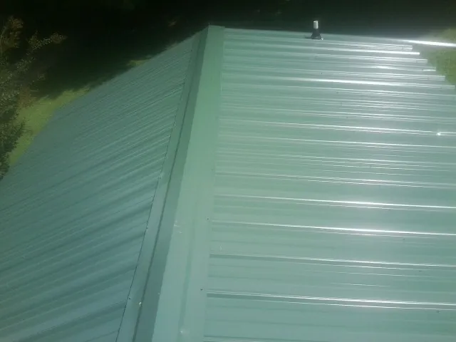 New green metal panels meeting at the ridge of a roof in Birds Landing
