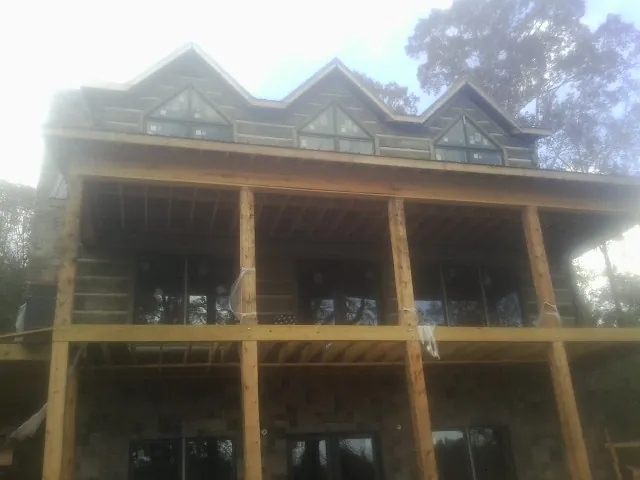 Dormers and porch framing on a large log home under construction — Roof Coating work by our crew in Birds Landing