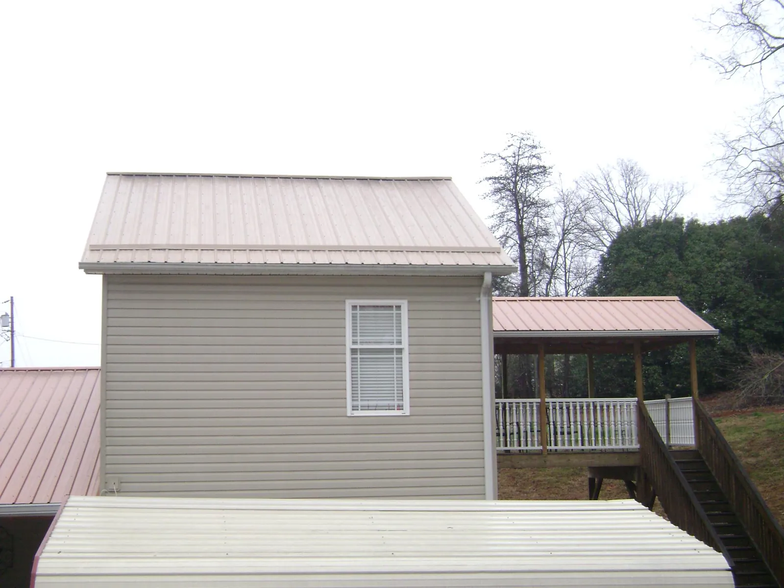 Tan metal roofs on a two story addition and attached porch, from a Roof Replacement job in Birds Landing
