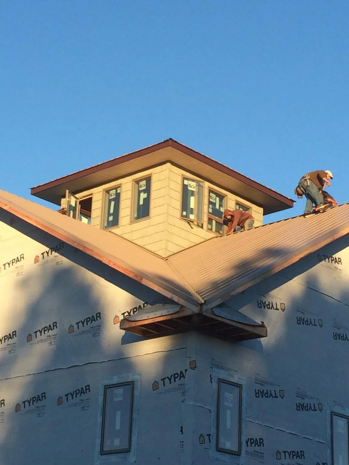 Roofers working around a rooftop cupola on a new metal roof at sunset — Roof Waterproofing in Birds Landing by Roofing Brothers